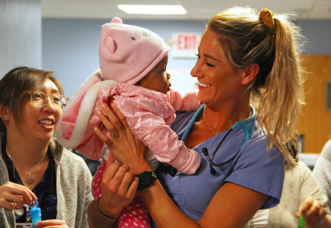 a nurse smiling while holding a baby girl