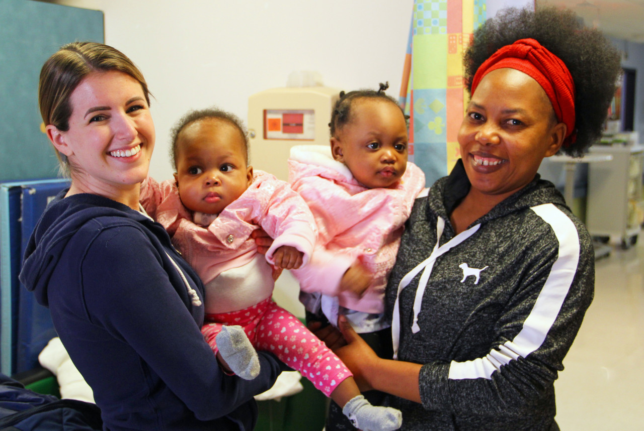 two medical providers holding twins and smiling