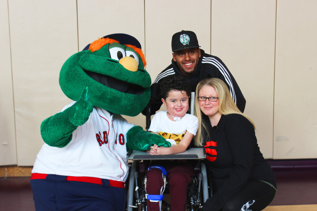 a boy next his parents and the red sox mascot