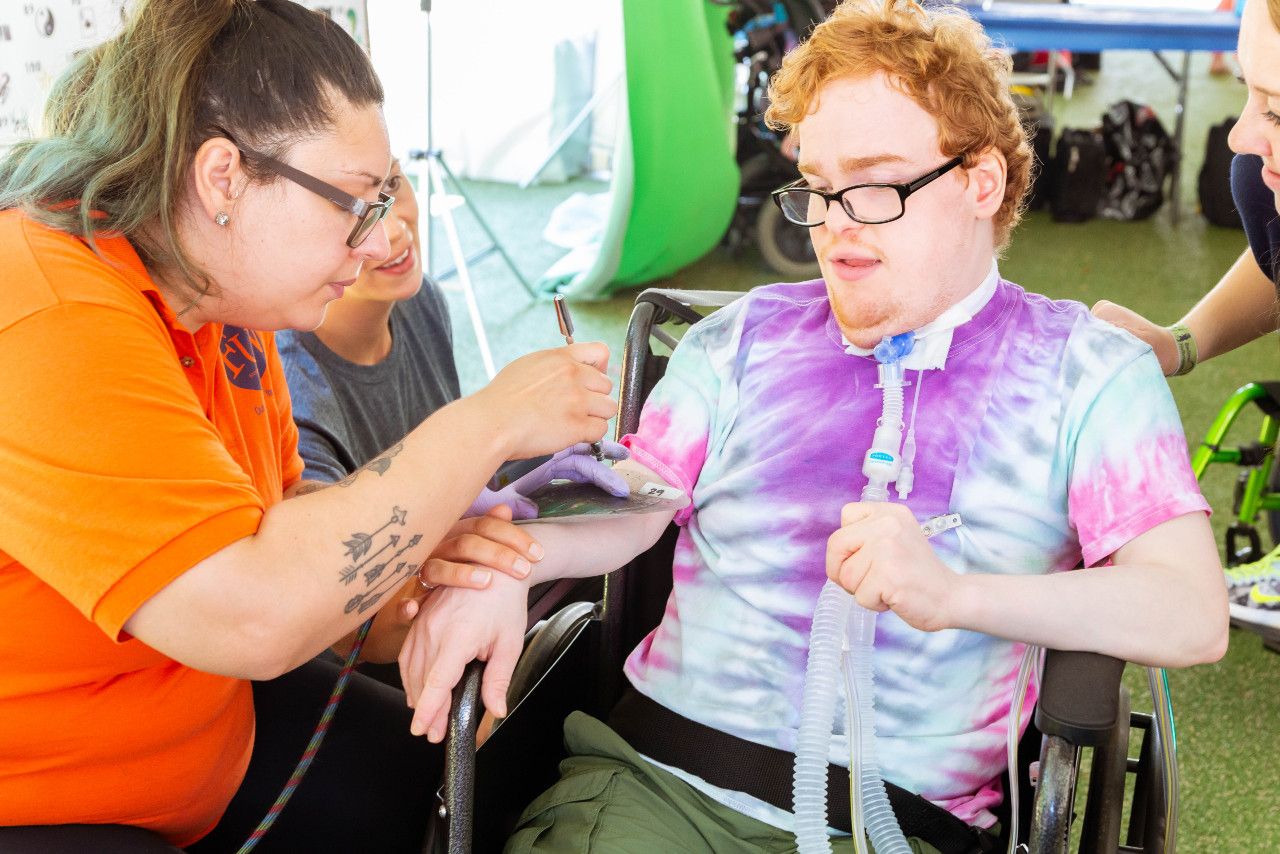a young man in a wheelchair being helped by a woman