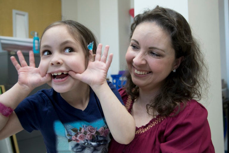 a smiling girl next to her mom