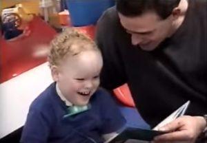 a young boy reading with the help of a man