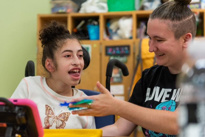 a teacher helping a young girl in a wheelchair
